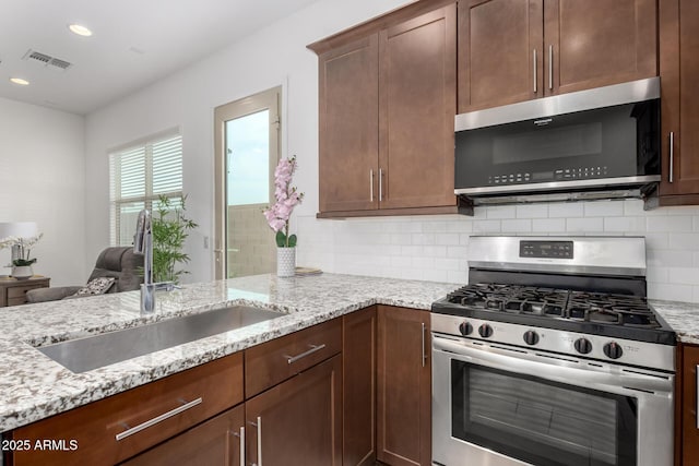 kitchen featuring sink, decorative backsplash, light stone countertops, and gas stove