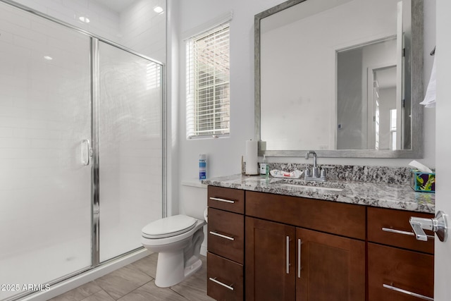 bathroom with vanity, a shower with door, and toilet