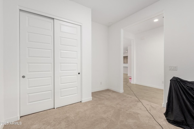 unfurnished bedroom with light carpet and a closet