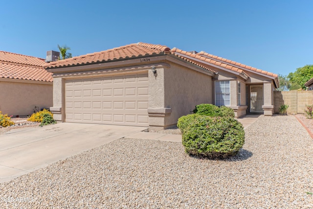 mediterranean / spanish-style house with a garage, concrete driveway, stucco siding, a tiled roof, and fence