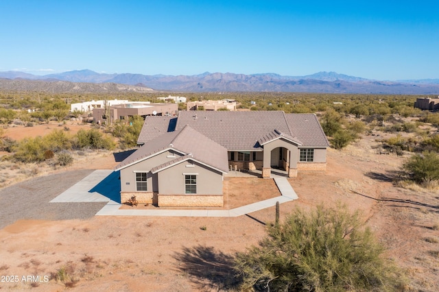 view of front of home with driveway, a tiled roof, a mountain view, and stucco siding