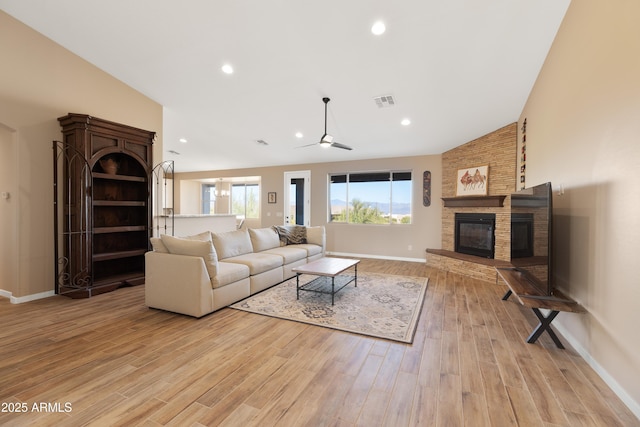 living room featuring light wood finished floors, baseboards, visible vents, a fireplace, and recessed lighting