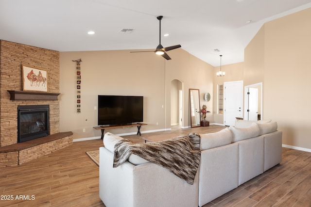 living area with visible vents, arched walkways, wood finished floors, and a stone fireplace