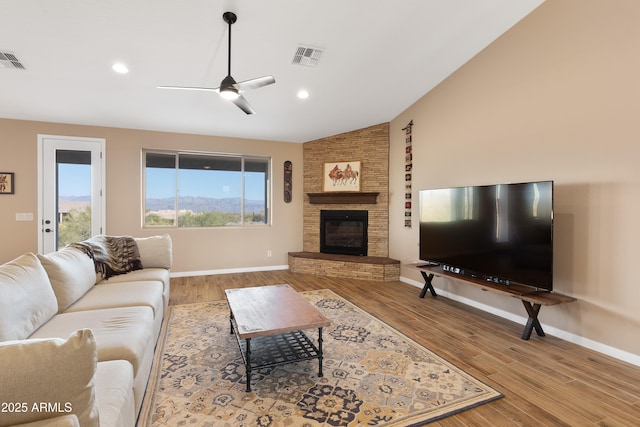 living area with light wood finished floors, a large fireplace, baseboards, visible vents, and lofted ceiling