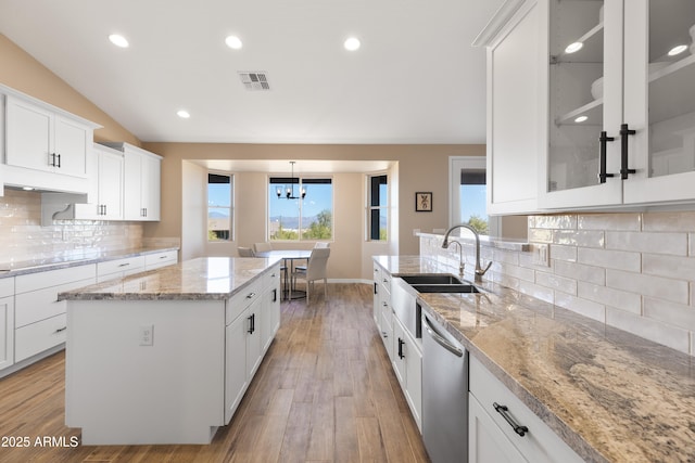 kitchen with visible vents, white cabinets, a center island, dishwasher, and glass insert cabinets