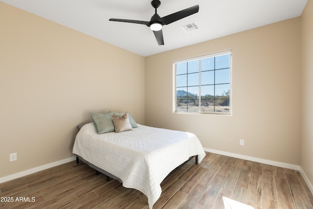 bedroom featuring a ceiling fan, visible vents, baseboards, and wood finished floors