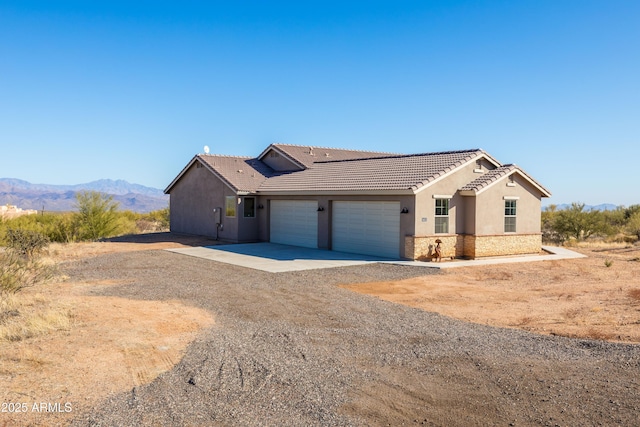 single story home featuring driveway, a garage, a tile roof, a mountain view, and stucco siding