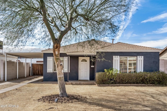 ranch-style home featuring a carport, a front yard, fence, and stucco siding