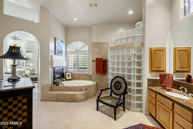 bathroom with ceiling fan, vanity, a healthy amount of sunlight, and plus walk in shower