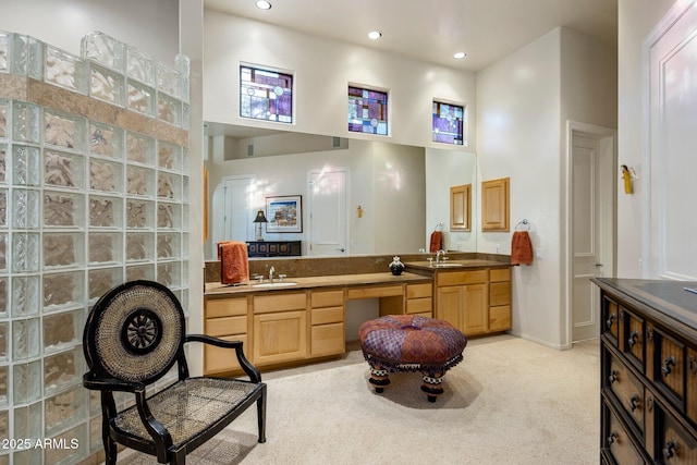 kitchen featuring light brown cabinetry, sink, a towering ceiling, and light colored carpet