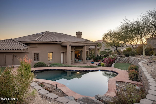 pool at dusk featuring a patio