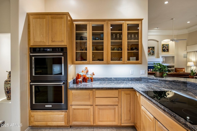 kitchen with double oven, ceiling fan, black electric stovetop, and dark stone counters