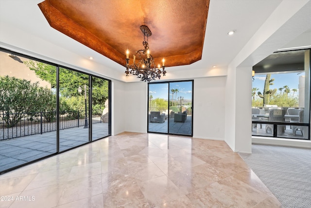 spare room featuring a tray ceiling and a notable chandelier