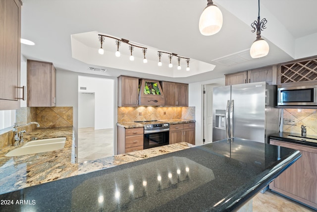 kitchen with sink, a tray ceiling, hanging light fixtures, and appliances with stainless steel finishes