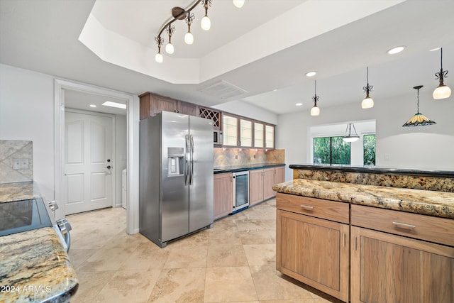 kitchen with appliances with stainless steel finishes, hanging light fixtures, wine cooler, decorative backsplash, and a raised ceiling