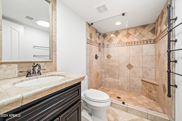 bathroom with a tile shower, vanity, and toilet