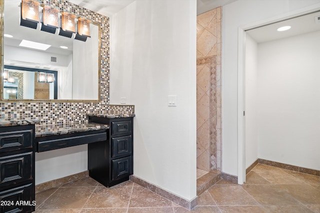 bathroom featuring vanity, decorative backsplash, and a tile shower