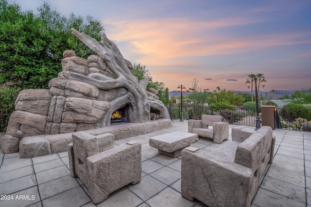 patio terrace at dusk featuring an outdoor stone fireplace