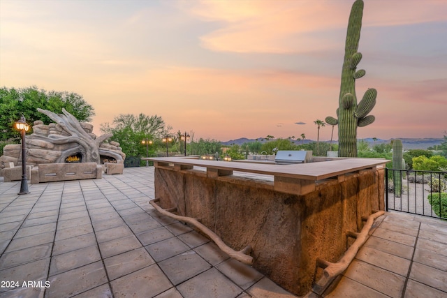 patio terrace at dusk with a mountain view and area for grilling