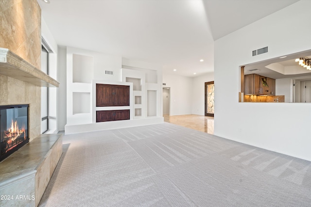 unfurnished living room with built in shelves, light colored carpet, a fireplace, and a wealth of natural light