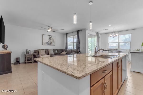 kitchen featuring ceiling fan with notable chandelier, light tile patterned floors, a center island with sink, and sink