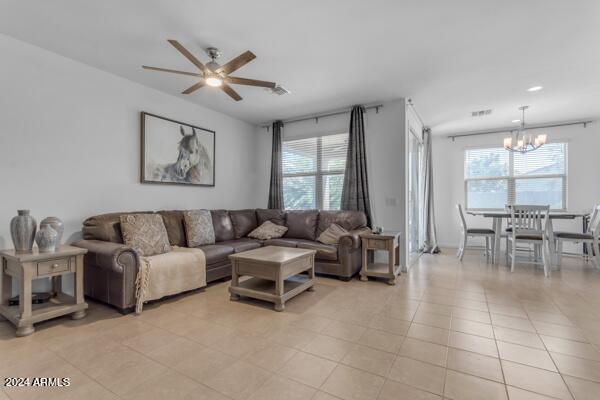 living room with ceiling fan with notable chandelier, a wealth of natural light, and light tile patterned floors