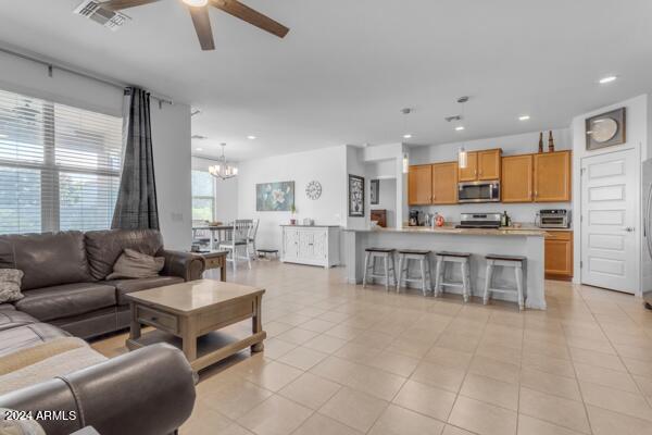 living room featuring ceiling fan with notable chandelier and light tile patterned floors