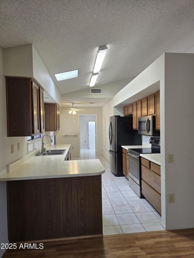 kitchen featuring a sink, light countertops, range with electric cooktop, stainless steel microwave, and visible vents