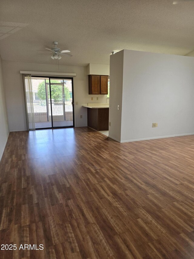 unfurnished living room with a ceiling fan, dark wood-style flooring, and a textured ceiling