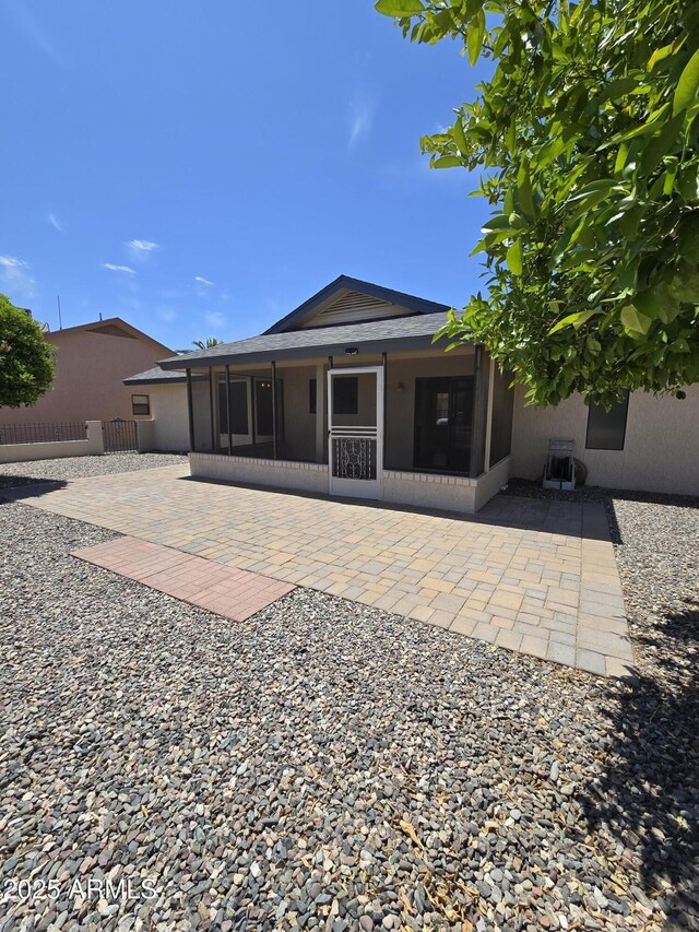 back of house featuring fence, a patio, stucco siding, and a sunroom