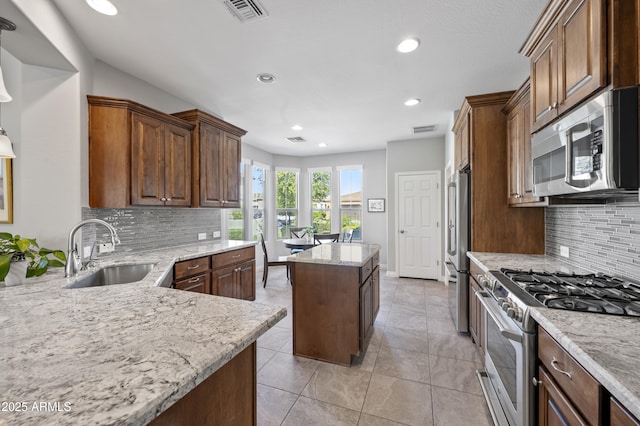 kitchen with light stone counters, visible vents, a kitchen island, a sink, and stainless steel appliances