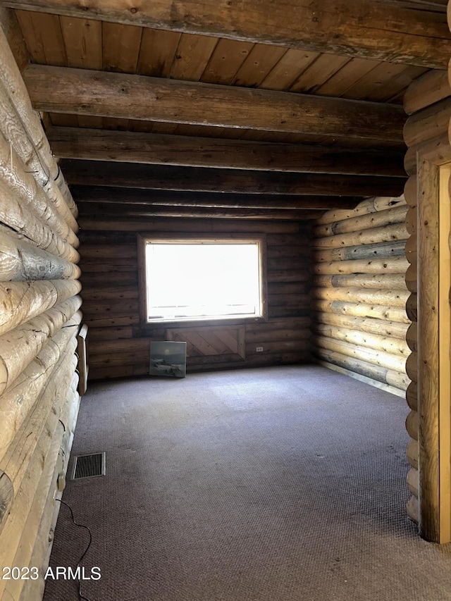 carpeted empty room with wooden ceiling, rustic walls, and beamed ceiling