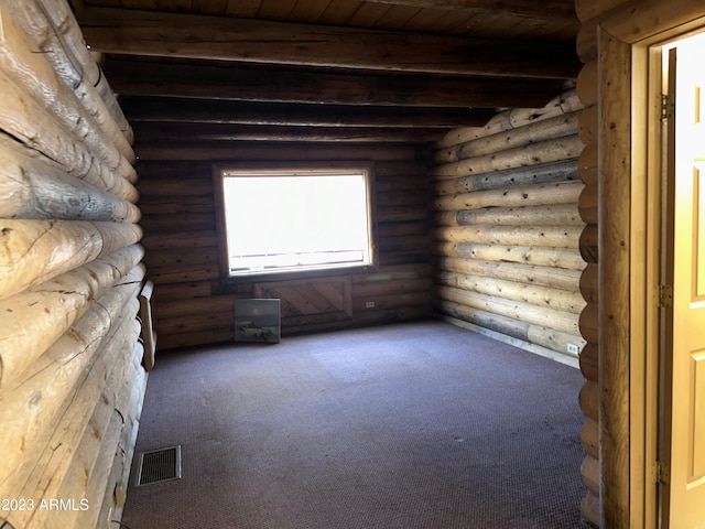 carpeted empty room featuring beam ceiling, log walls, and wooden ceiling