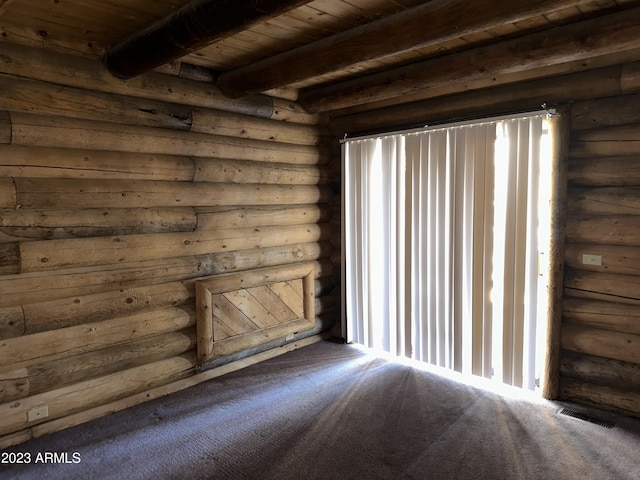 carpeted spare room featuring rustic walls, wooden ceiling, and beam ceiling