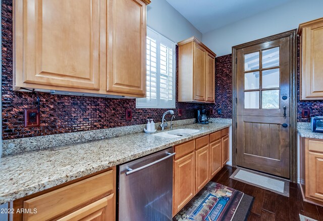 kitchen featuring dark wood-type flooring, light stone counters, tasteful backsplash, stainless steel dishwasher, and sink