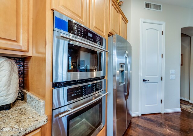 kitchen featuring light stone countertops, light brown cabinets, appliances with stainless steel finishes, and dark hardwood / wood-style flooring