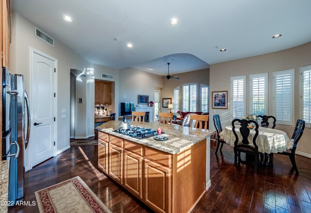 kitchen with dark hardwood / wood-style flooring, ceiling fan, a center island, and gas cooktop