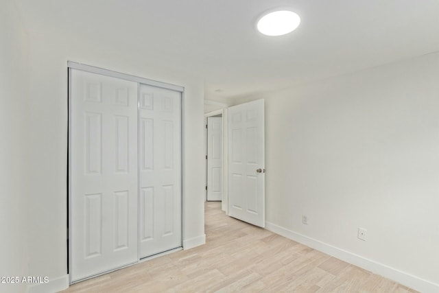 unfurnished bedroom with light hardwood / wood-style flooring and a closet