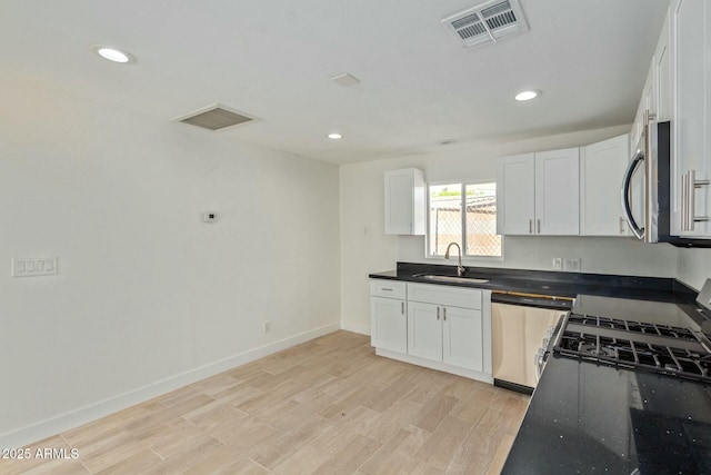 kitchen with white cabinetry, sink, stainless steel appliances, and light hardwood / wood-style floors