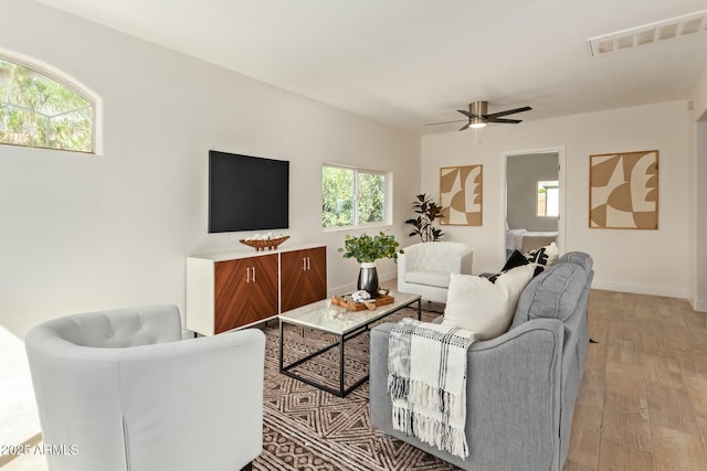 living room with ceiling fan, plenty of natural light, and light wood-type flooring