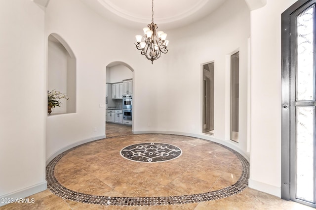 hallway with a high ceiling and an inviting chandelier