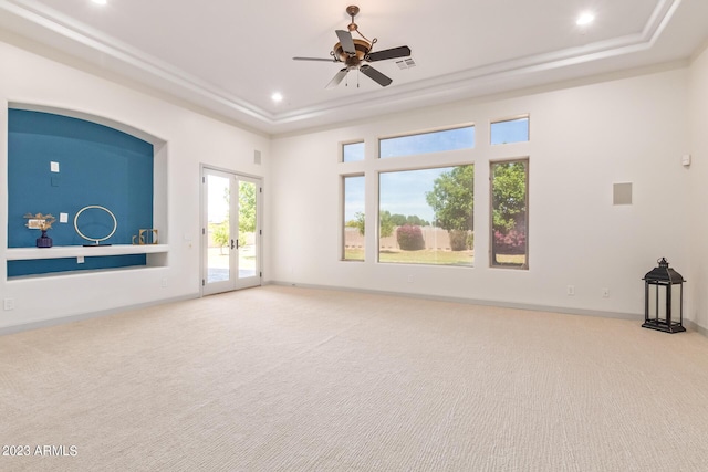 unfurnished living room featuring carpet flooring, ceiling fan, french doors, and a tray ceiling