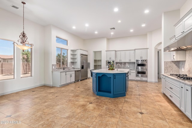 kitchen with a breakfast bar, a high ceiling, decorative light fixtures, and a kitchen island with sink