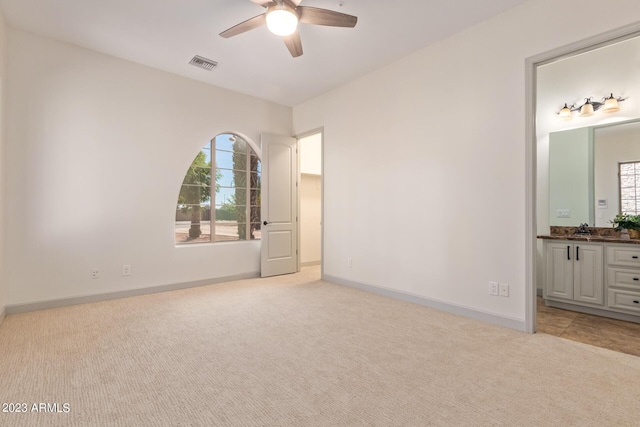 unfurnished bedroom featuring multiple windows, light carpet, sink, and ceiling fan