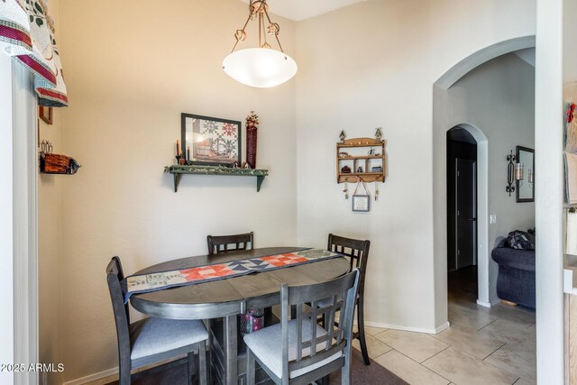 12318 W Bloomfield Rd, El Mirage, AZ 85335 - dining area featuring arched walkways, light tile patterned floors, and baseboards