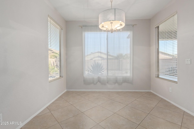 spare room featuring light tile patterned flooring and an inviting chandelier