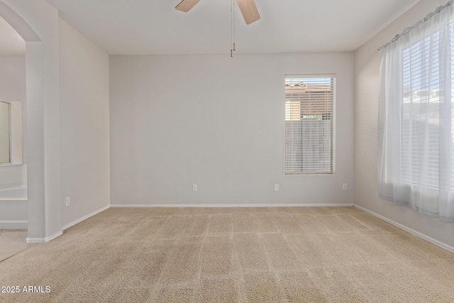 spare room featuring ceiling fan, light colored carpet, and a healthy amount of sunlight