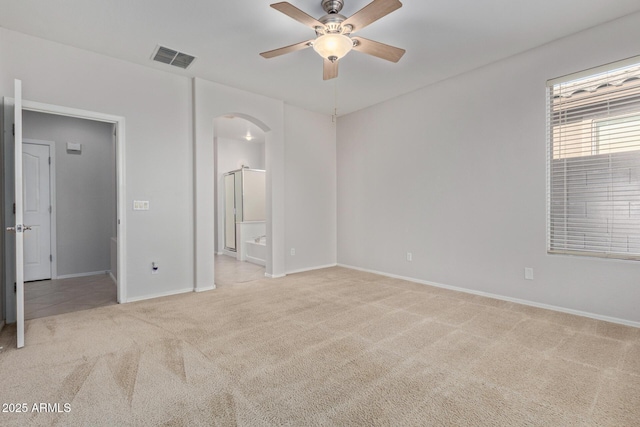 unfurnished bedroom with connected bathroom, light colored carpet, and ceiling fan