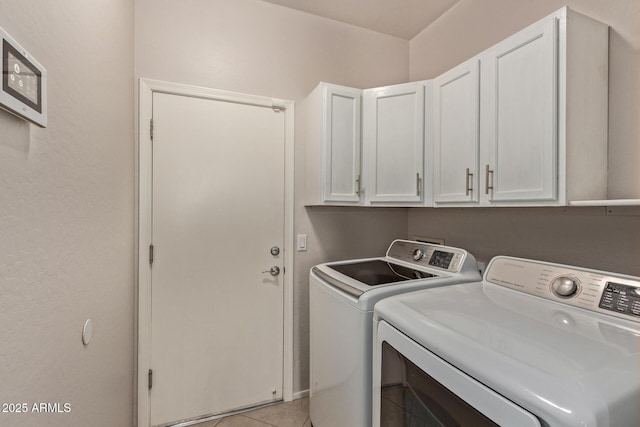 clothes washing area with cabinets, washing machine and dryer, and light tile patterned floors