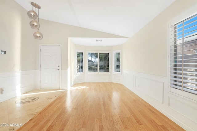 unfurnished room with plenty of natural light, light hardwood / wood-style flooring, and lofted ceiling